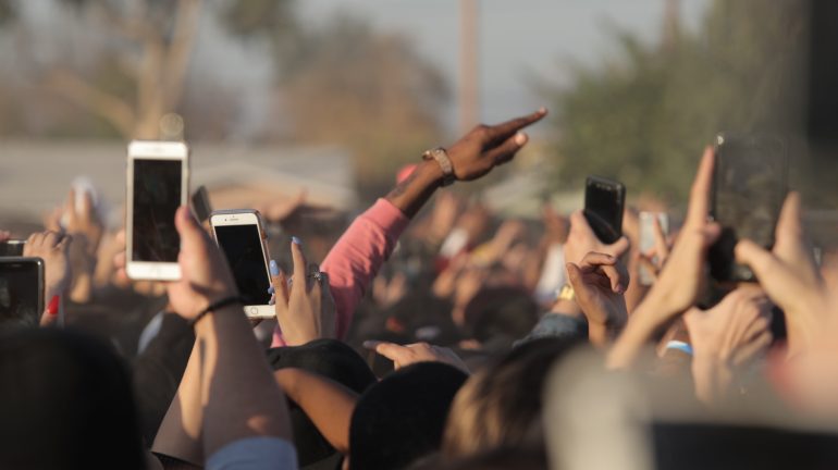 hands of people holding up their phones at event